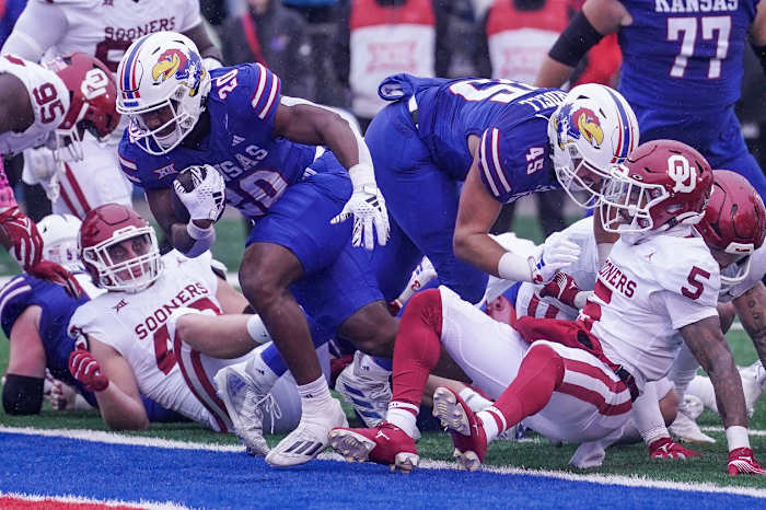 Oct 28, 2023; Lawrence, Kansas, USA; Kansas Jayhawks running back Daniel Hishaw Jr. (20) scores as Oklahoma Sooners defensive lineman Ethan Downs (40) and defensive back Woodi Washington (5) look on during the second half at David Booth Kansas Memorial Stadium.